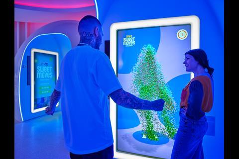 Two customers interacting with M&M's Berlin store clubbing pods. Sign says 'M&M Sweet Moves'